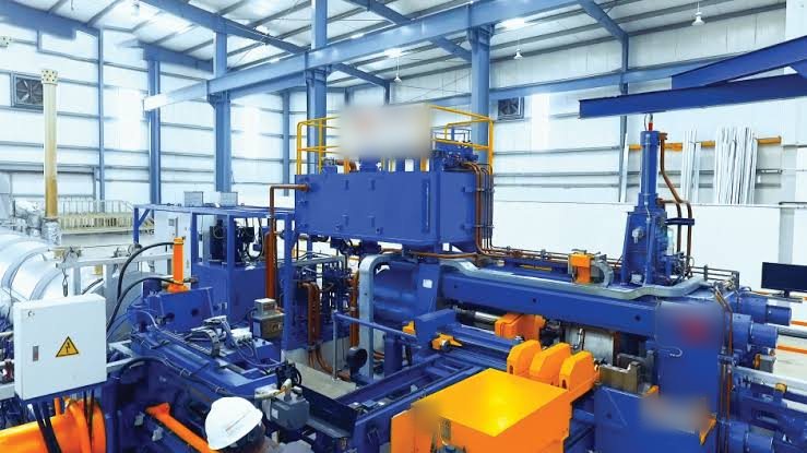 Aluminium extrusion press line inside a partner plant, with operator in hard hat